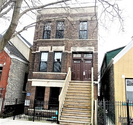A brown wooden staircase leads to a door on a brick building.