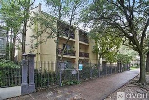 A building with a fence and trees in front of it.
