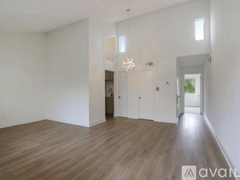 A spacious room with wooden floors and white walls.