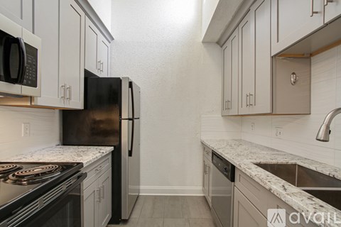 A kitchen with a black refrigerator and white cabinets.