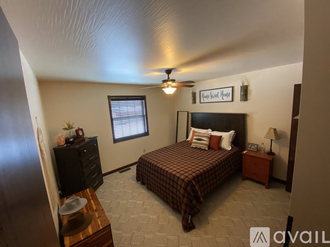 A bedroom with a bed, dresser, and ceiling fan.