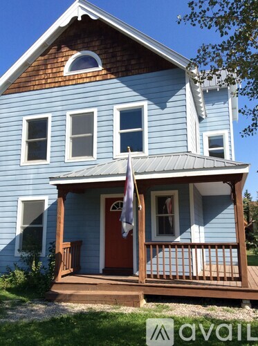 A blue house with a red door and a flag on the porch.