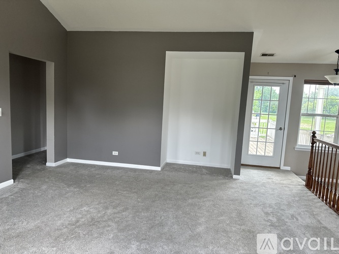 A spacious room with grey carpeting and white walls is available for rent.