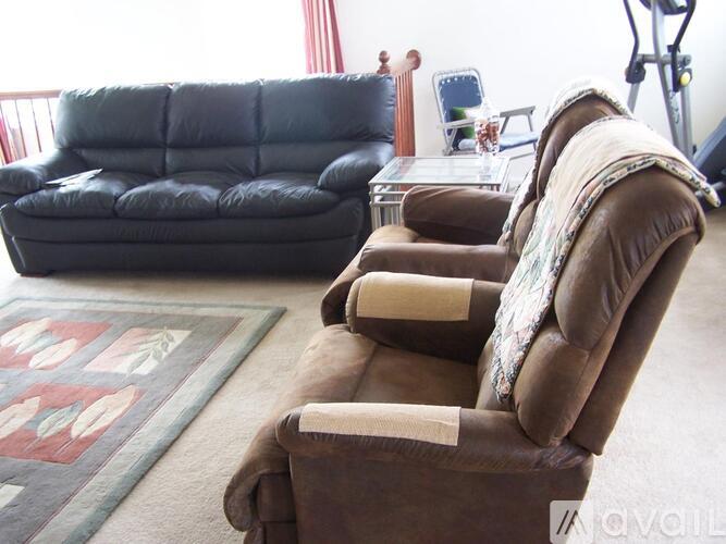 A brown recliner chair with a cushion is in the foreground of a living room.