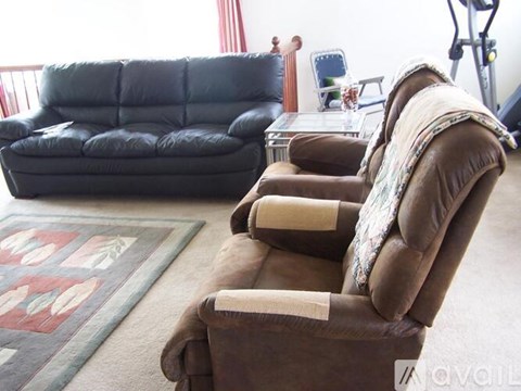 A brown recliner chair with a cushion is in the foreground of a living room.