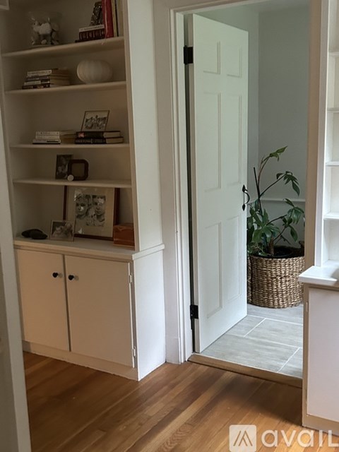 A room with a white door and a cabinet with shelves.