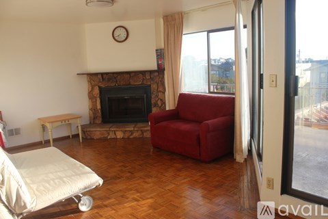 A living room with a red chair and a fireplace.