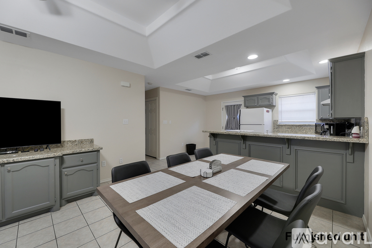 A kitchen with a table set for four with papers on it.