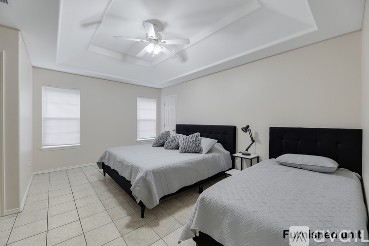A bedroom with two beds, one with a black headboard and the other with a white headboard.
