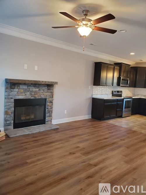 A living room with a stone fireplace and wooden floors.