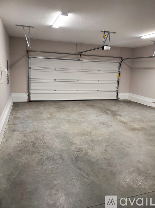 A spacious garage with a white roll-up door and a concrete floor.