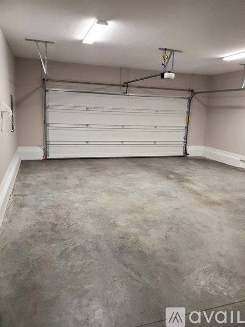 A spacious garage with a white roll-up door and a concrete floor.