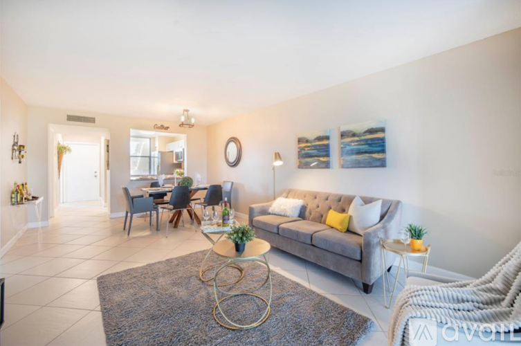 A living room with a grey couch, a coffee table, and a dining table with chairs.