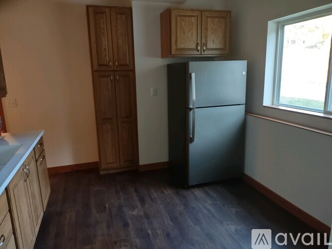 A kitchen with a black refrigerator and wooden cabinets.