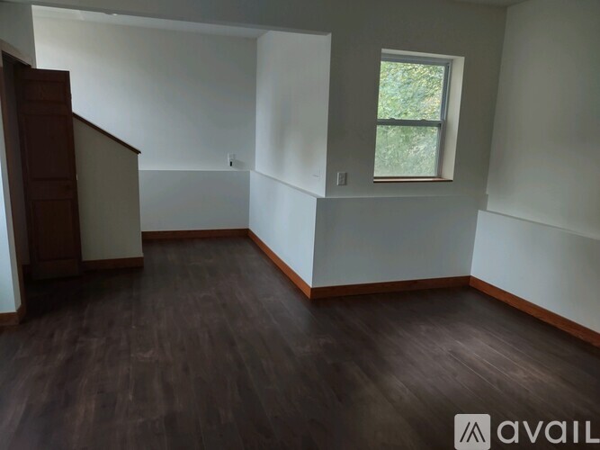 A room with wooden floors and a window with a view of trees outside.