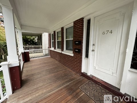 A porch with a white door and a mailbox on it.