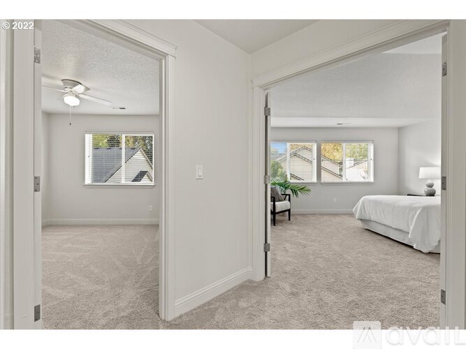 A bedroom with a bed, a chair, and a window overlooking a street.