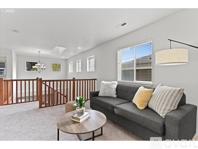 A living room with a grey couch, a coffee table, and a wooden staircase.