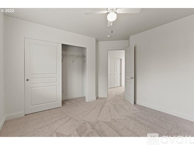 A spacious room with a carpeted floor and a ceiling fan.