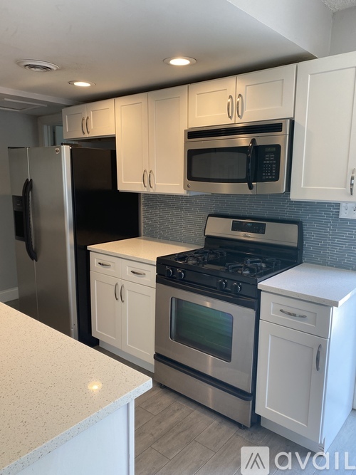 A kitchen with white cabinets and a stainless steel refrigerator.