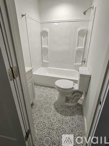 A bathroom with a toilet, tub, and tiled floor.