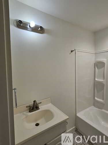 A white bathroom with a sink, mirror, and shower.