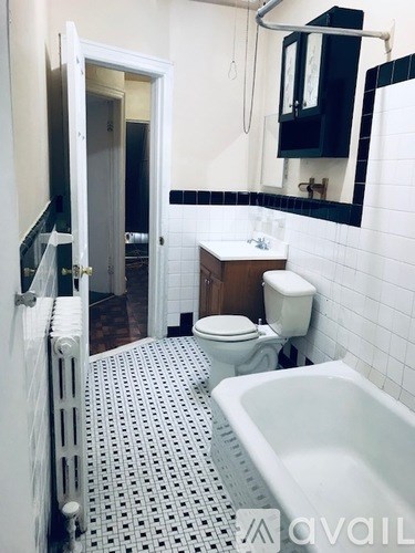 A white toilet sits in a bathroom with a white bathtub and a white sink.