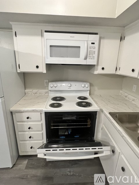 A white kitchen with a stove and microwave mounted on the wall.