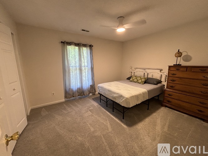 A bedroom with a bed, dresser, and carpeted floor.