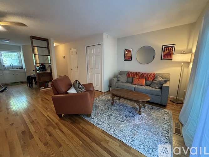 A living room with a brown chair, a grey couch, and a wooden floor.
