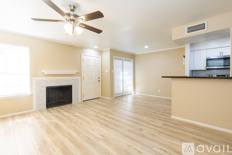 A spacious living room with a fireplace and a ceiling fan.