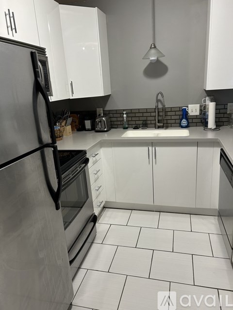 A kitchen with white cabinets and a black refrigerator.