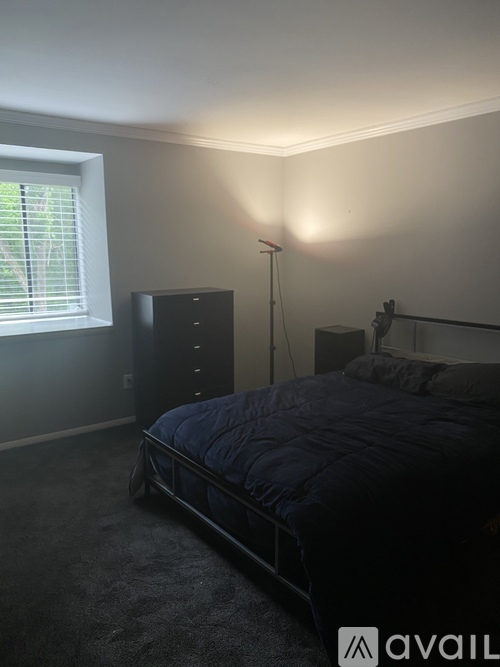 A bedroom with a bed, nightstand, and window.