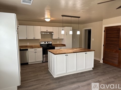 A kitchen with white cabinets and a wooden island.