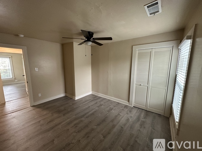 A spacious room with a ceiling fan and sliding door.