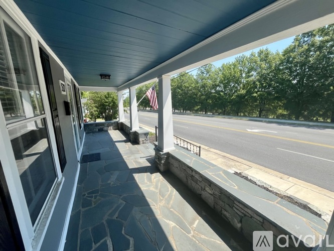 A train station platform with a view of the road and trees.