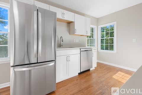 A kitchen with a stainless steel refrigerator and white cabinets.