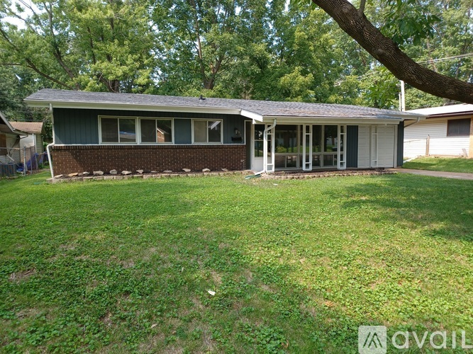 A house with a green roof and a white garage door is for sale.