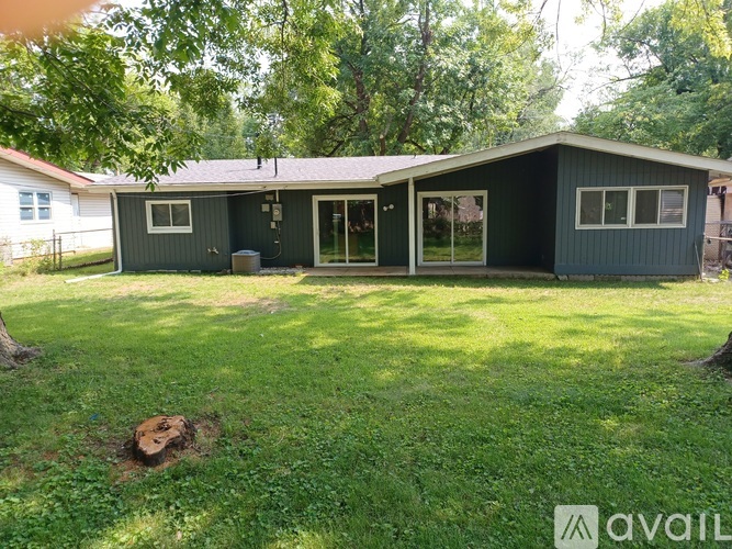 A house with a green lawn and trees in the background.