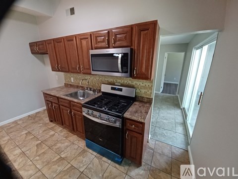 A kitchen with brown cabinets and a black stove top oven.