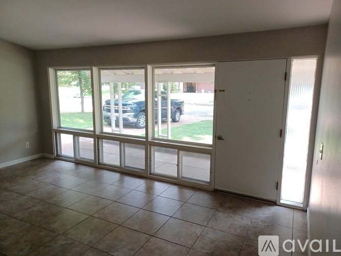 A room with a sliding glass door leading to a parking lot.