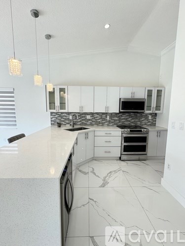 A modern kitchen with white cabinets and marble countertops.