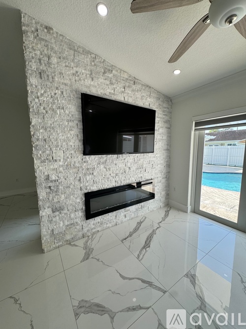 A modern living room with a stone fireplace and a flat screen TV mounted above it.