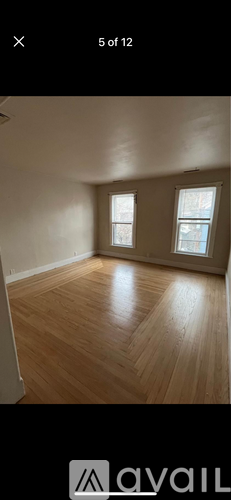 A room with wooden flooring and two windows.