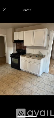 A kitchen with a black stove top oven and white cabinets.