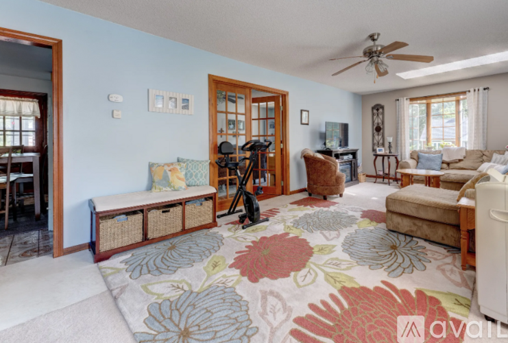 A living room with a rug on the floor and a ceiling fan.