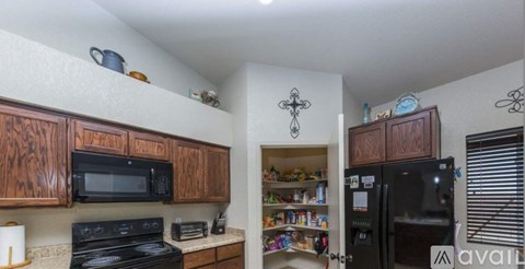 A kitchen with wooden cabinets and a black refrigerator.