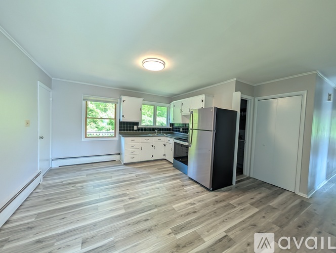 A kitchen with a refrigerator, sink, and cabinets.