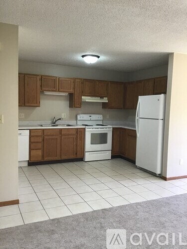 A kitchen with white appliances and brown cabinets.