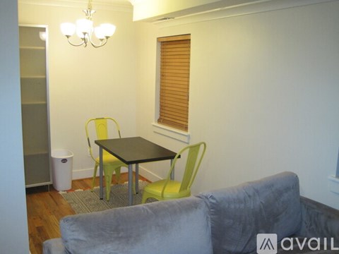 A living room with a grey couch, a black table and two chairs.